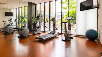 Un gimnasio con máquinas de cardio, cinta de correr y una pelota de ejercicio grande.