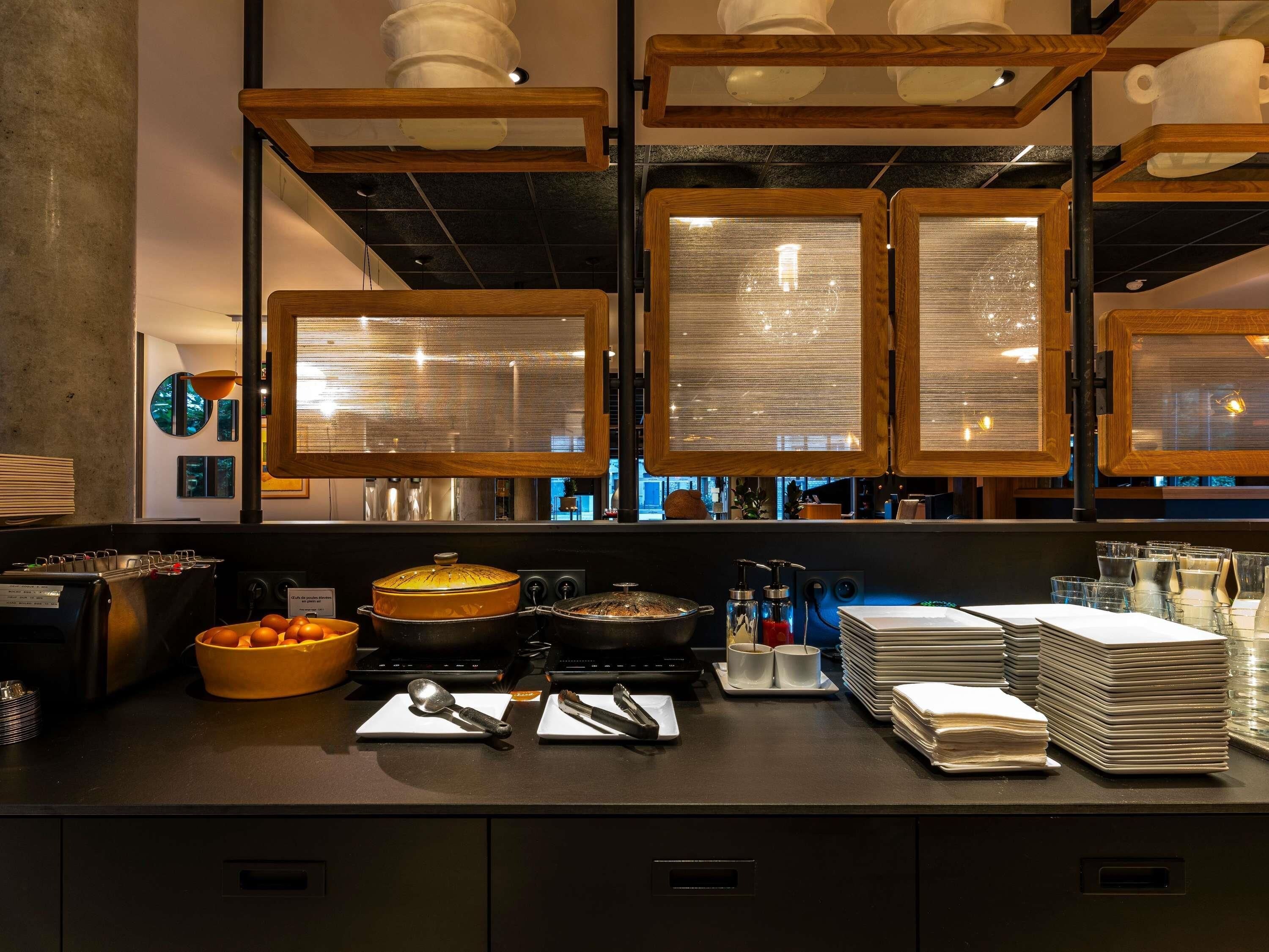 A buffet setup with various food items and utensils, a coffee machine, and a stack of napkins.