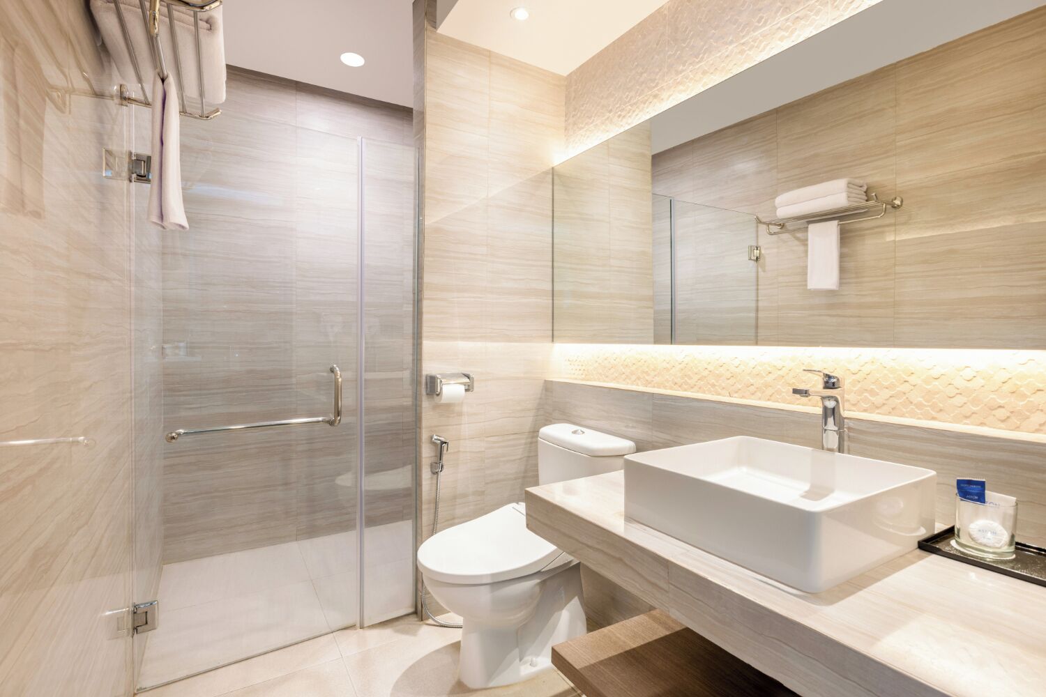 Un baño moderno con cabina de ducha de vidrio, inodoro y un lavamanos grande con espejo arriba.