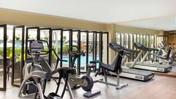 Un gimnasio con máquinas de cardio, una piscina y vistas al exterior.