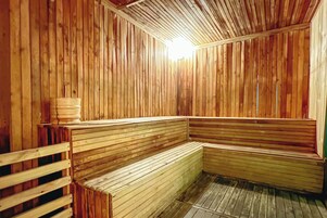 Uma sauna de madeira com bancos e um banco à esquerda.