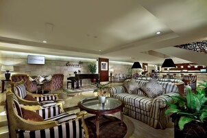 A spacious lobby with striped sofas, a round glass table, and a television mounted on the wall.