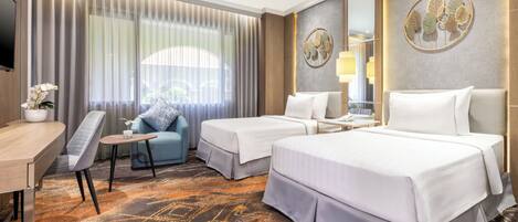 A hotel room with two beds, a desk, a chair, and a large window with curtains.