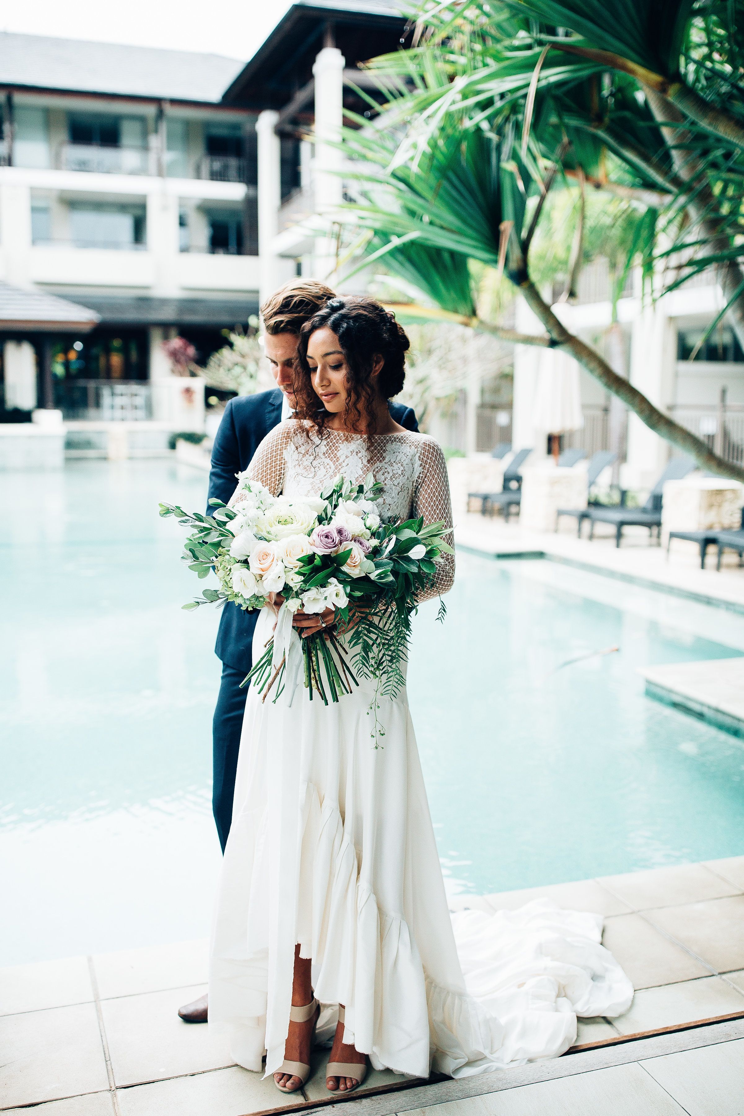 A couple by a pool with a modern building in the background.