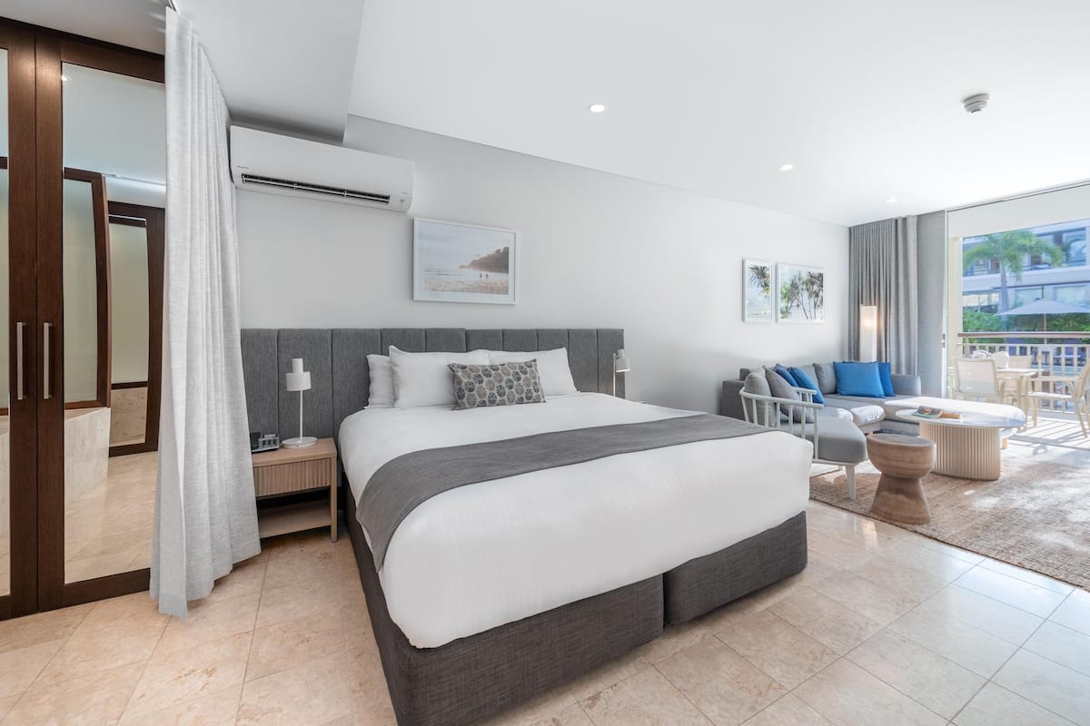 Une chambre d’hôtel moderne dotée d’un grand lit, d’un bureau, d’une chaise et d’un balcon aménagé avec du mobilier d’extérieur.