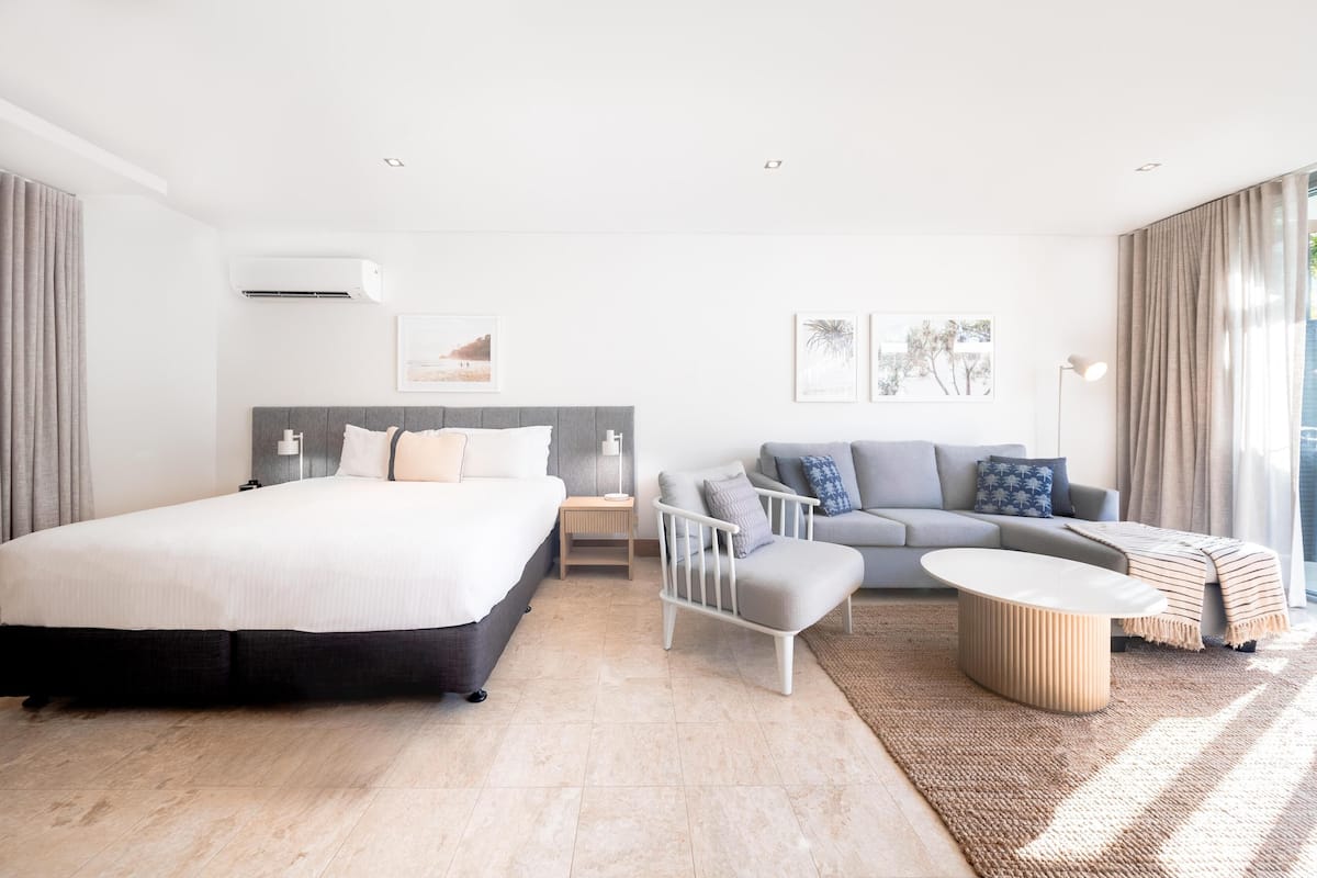 Une chambre d’hôtel moderne équipée d’un grand lit, d’un canapé, d’une table basse et d’un bureau.