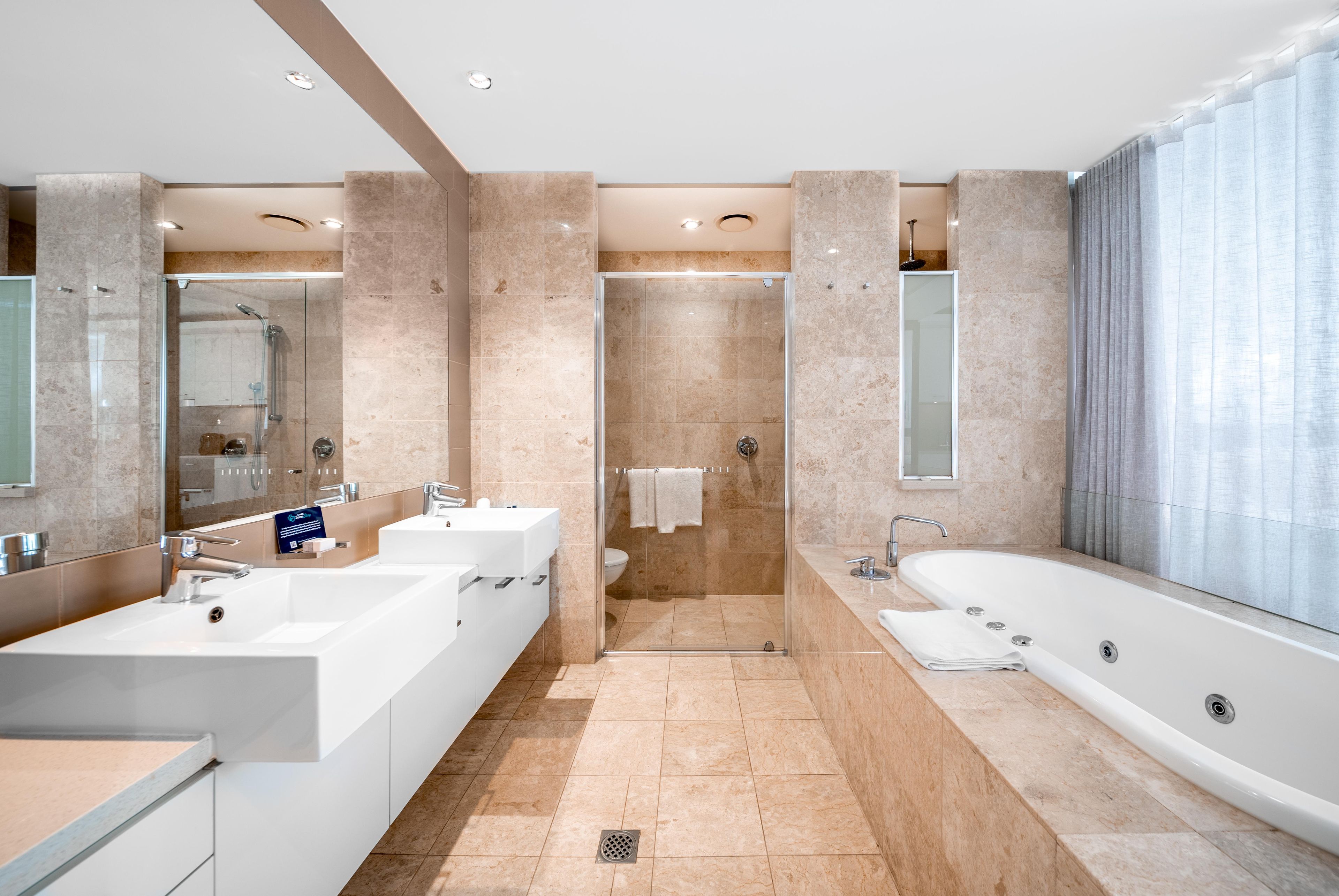 Ein modernes Badezimmer mit zwei Waschbecken, einer Dusche und einer Badewanne.