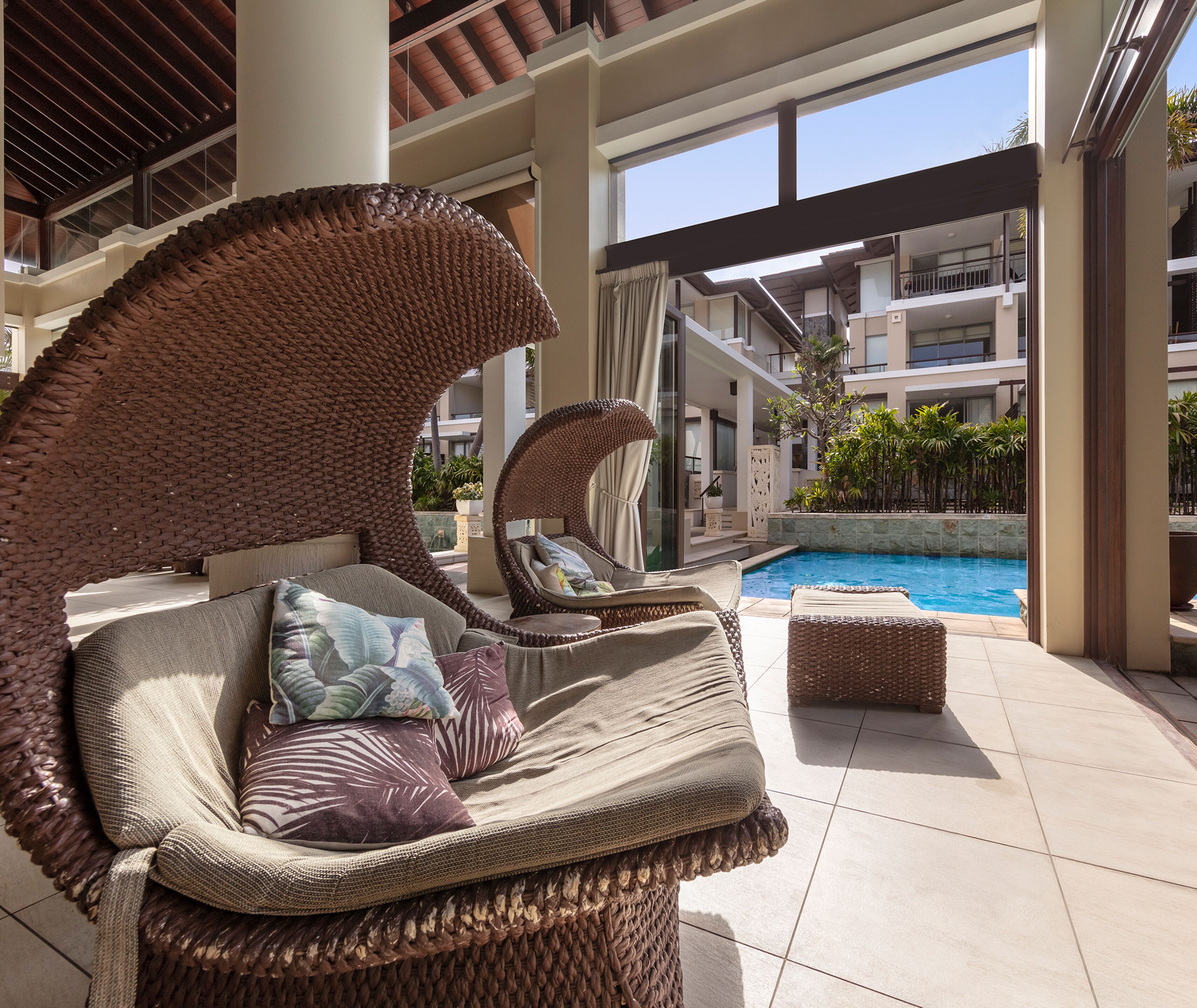 A poolside area with wicker lounge chairs and a pool.