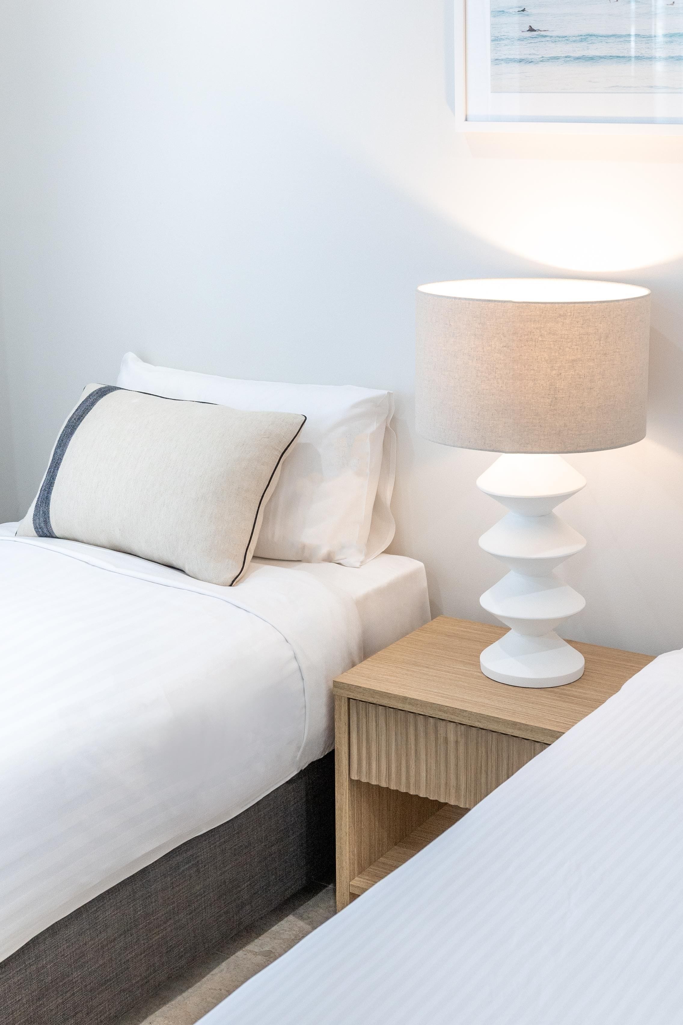 Une chambre d’hôtel avec un lit, une table de chevet et une lampe.