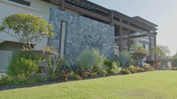 A modern building with a stone facade, a well-maintained lawn, and various plants and shrubs.