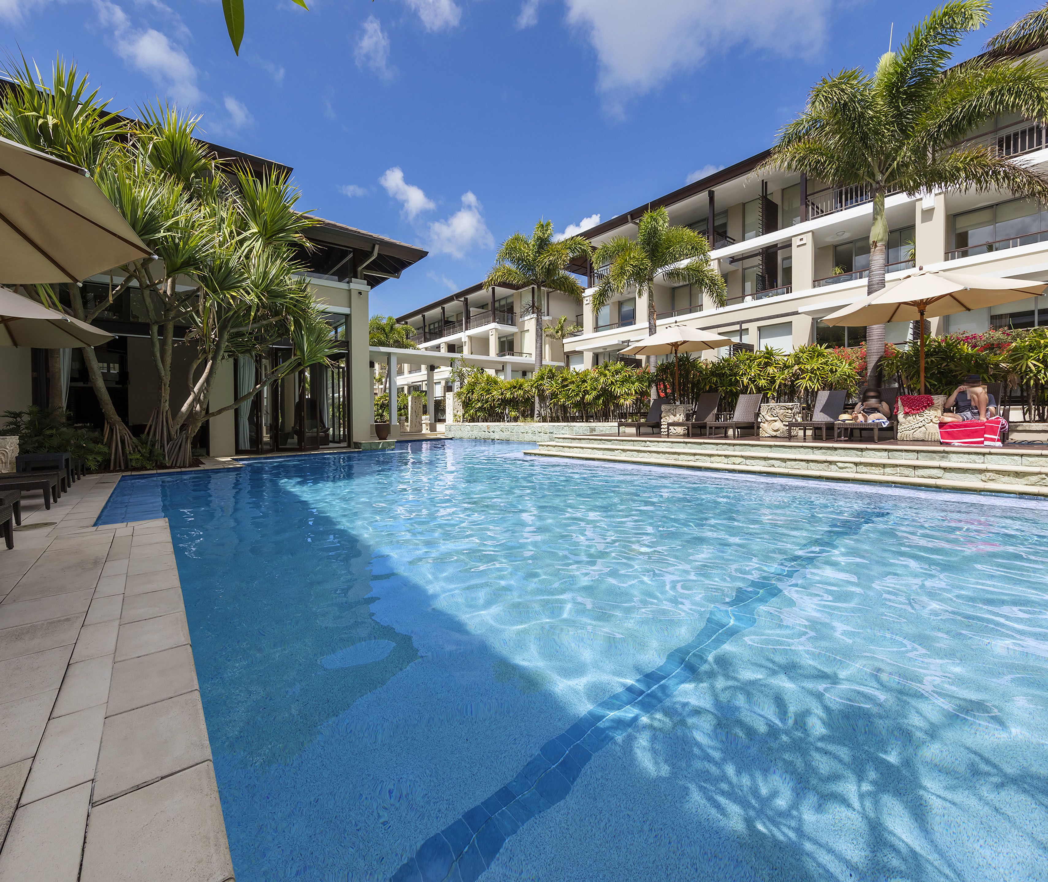 Una piscina al aire libre, sombrillas, sillones reclinables de piscina