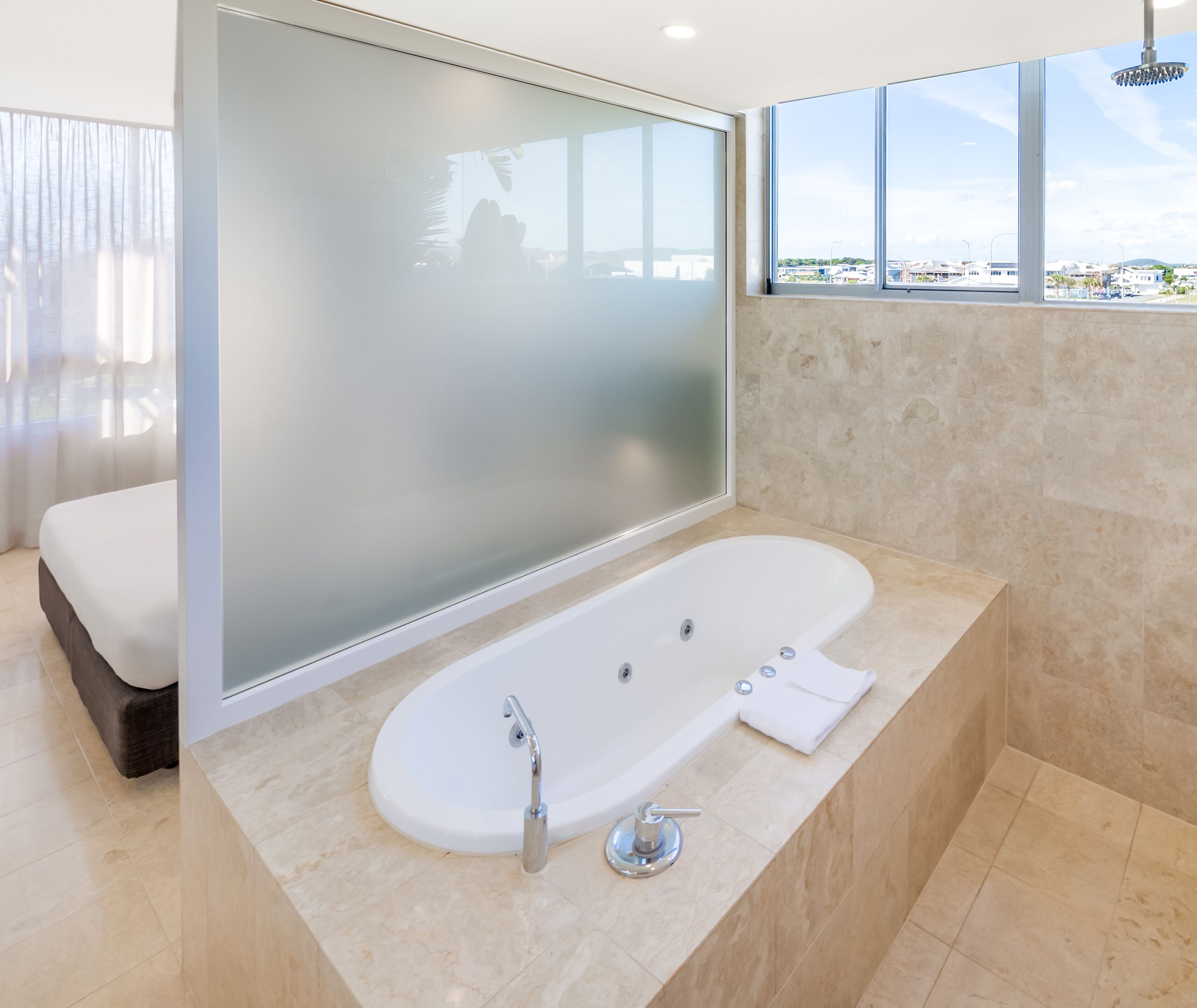 A modern bathroom with a freestanding bathtub, a large mirror, and a view of the city through large windows.