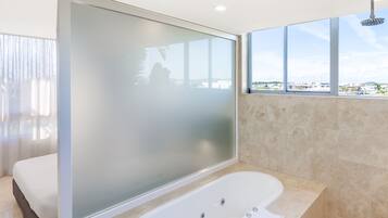 A modern bathroom with a freestanding bathtub, a large mirror, and a view of the city through large windows.