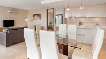 A modern kitchen with white cabinets, a glass dining table, and white chairs.