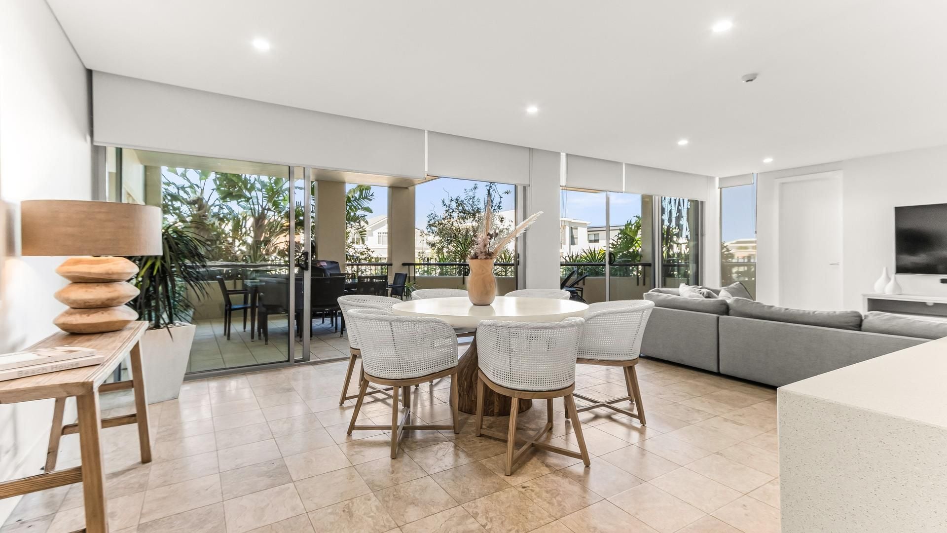 A modern living room with a dining area, a sofa, and a TV.