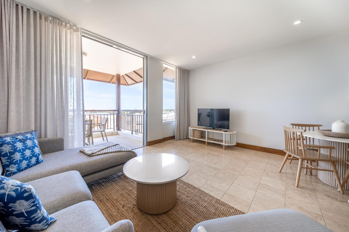Un salon moderne comprenant un canapé, une table basse, un téléviseur et un coin repas avec des chaises et une table.