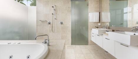 A modern bathroom with a large bathtub, a glass shower enclosure, and a vanity with a mirror.