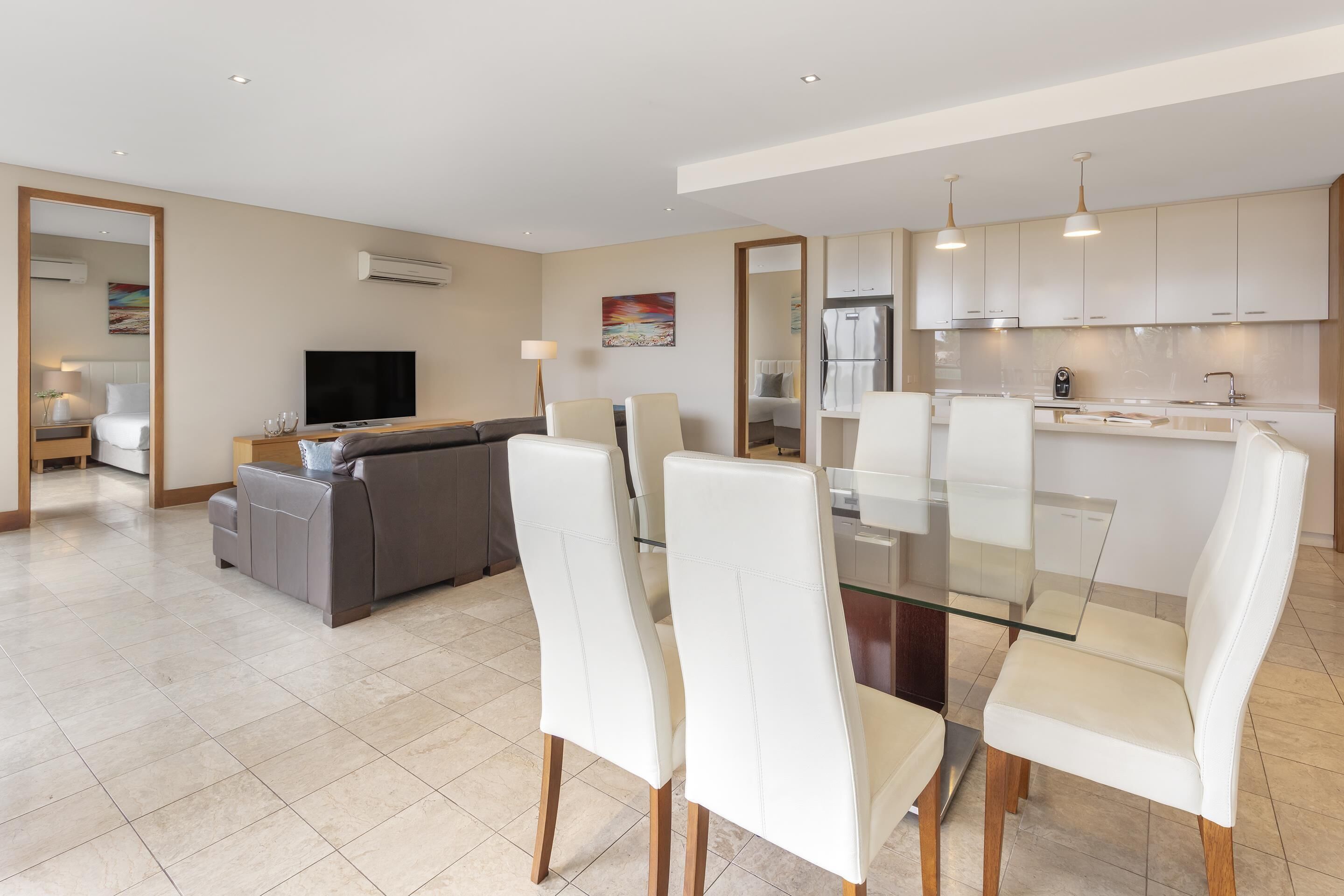 Una habitación de hotel moderna con comedor, sofá, televisor y cocina.