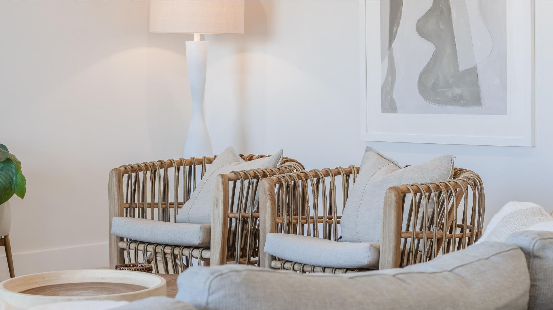 Um quarto com cadeiras de vime, uma mesa redonda de madeira e uma luminária.