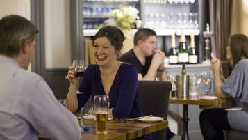 Uma área de bar com mesas, cadeiras, garrafas de vinho e copos.