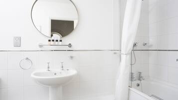A modern bathroom with a white sink, a round mirror, and a shower area.