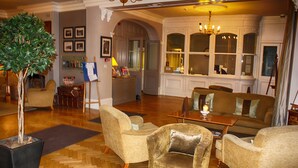 A spacious living room with a large chandelier, comfortable seating, and a potted tree. - The Bell Hotel (Sandwich)