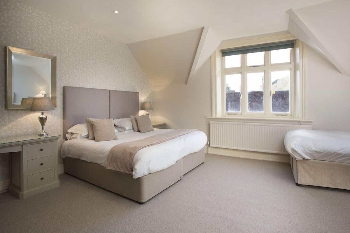 A bedroom with a large bed, bedside tables, a window with a view, and a radiator.