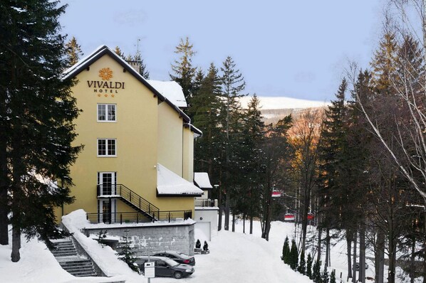 A yellow building with a sign reading "VIVALDI HOTEL" and a staircase leading to the entrance.