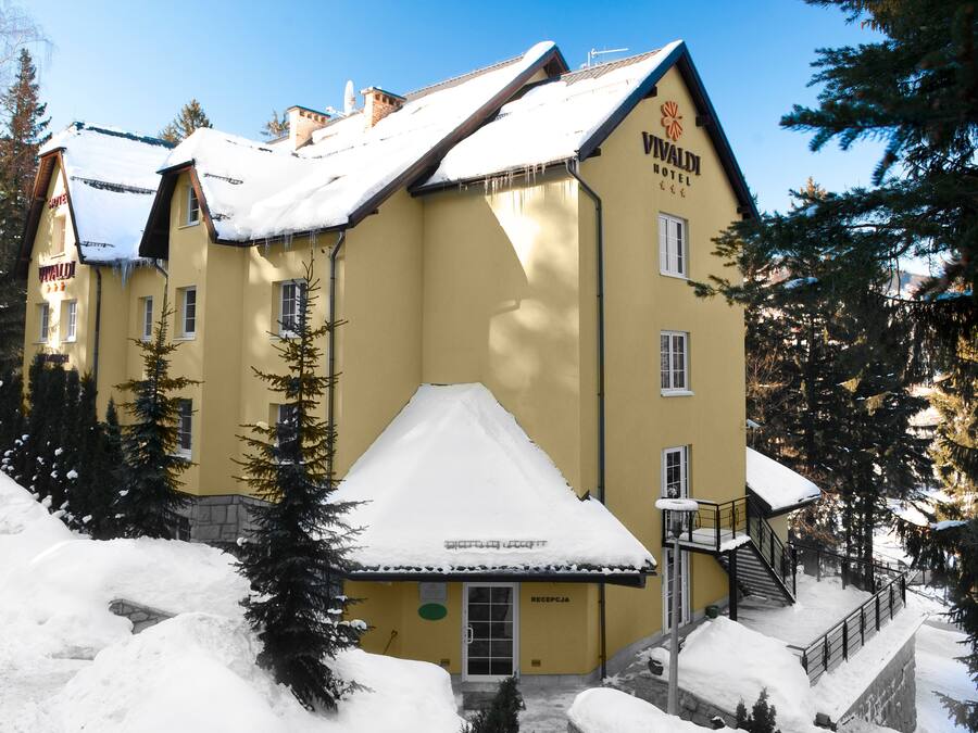 Un edificio amarillo con un letrero que dice "Vivaldi Hotel" y una zona de recepción.