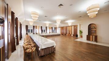 Ein großer Konferenzraum mit einem langen Tisch, Holzstühlen und modernen Leuchten.