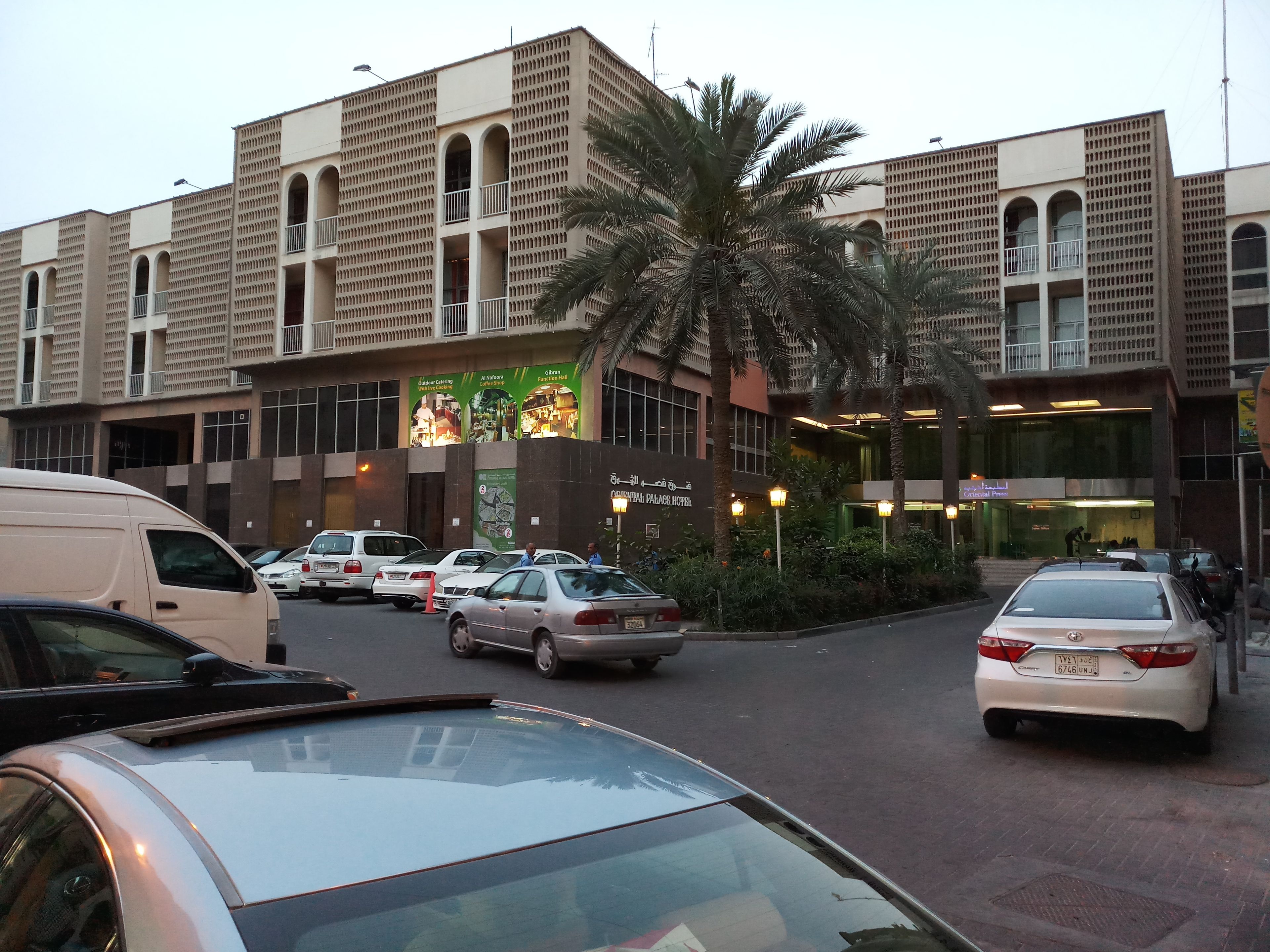 A multi-story building with a modern architectural design, featuring balconies and a central courtyard with palm trees.