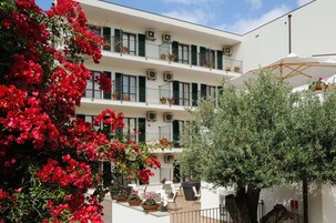 A multi-story building with balconies, potted plants, and outdoor seating.