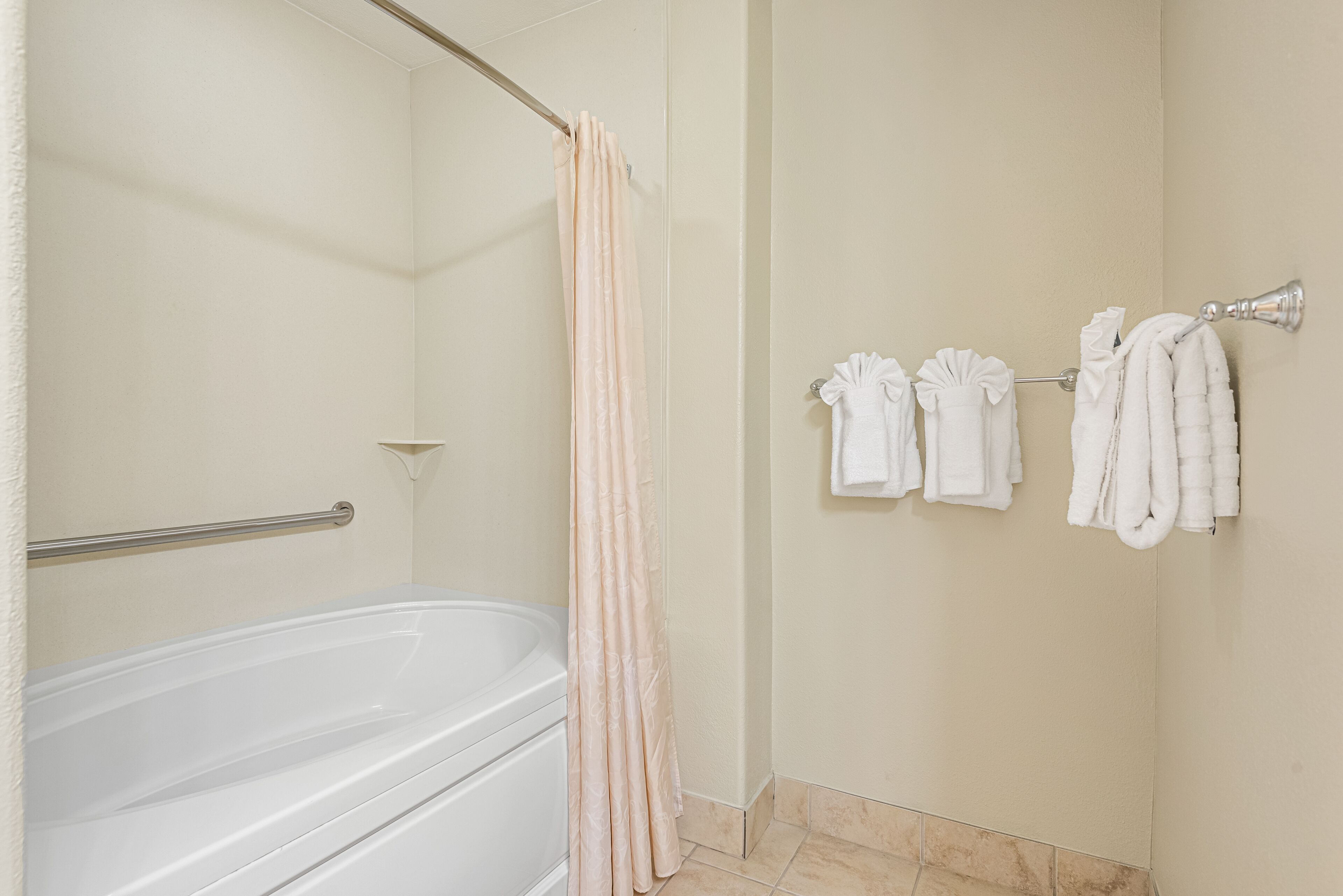 A bathroom with a bathtub, a shower curtain, and towels hanging on a rack.