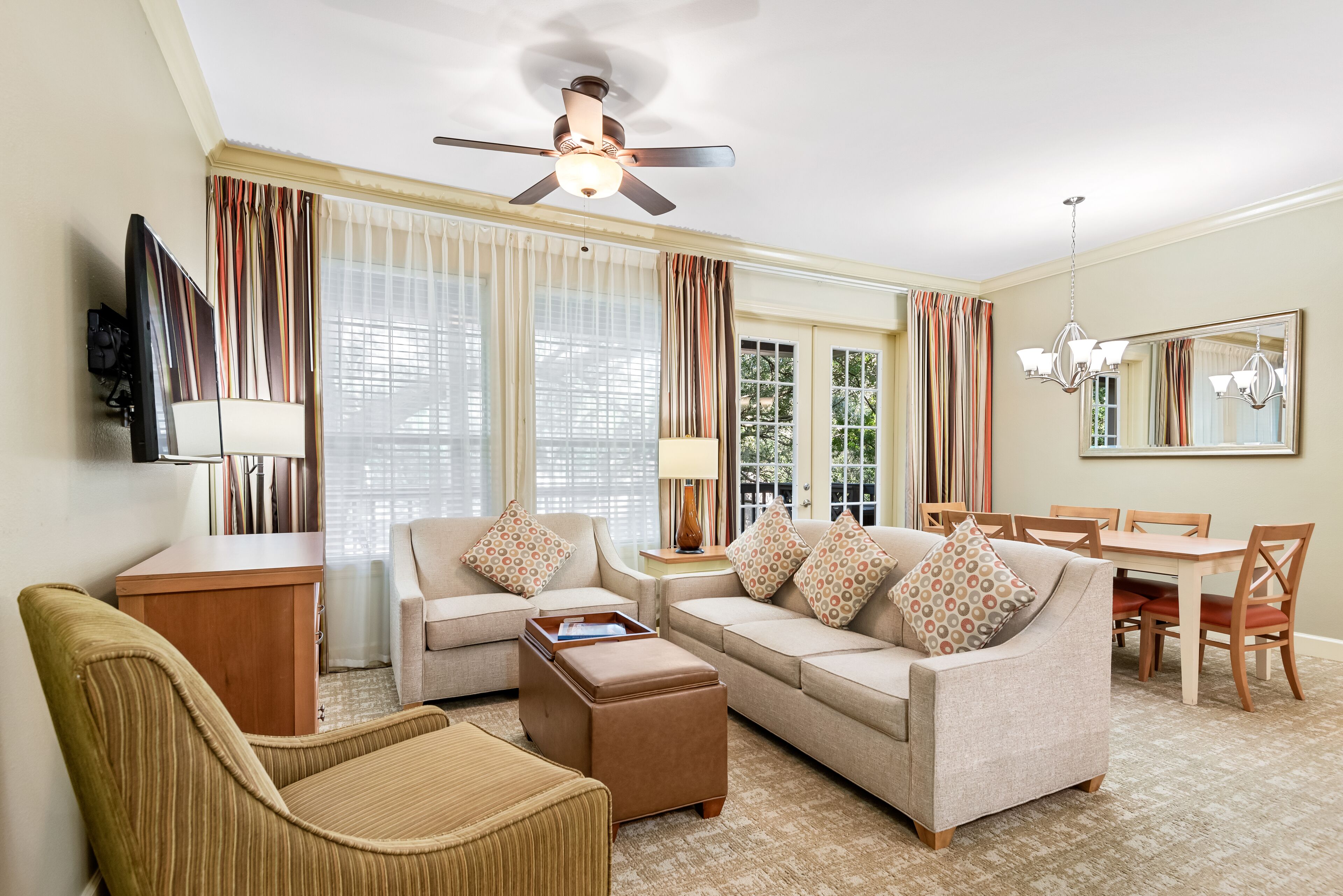 A living room with a sofa set, a coffee table, a TV, and a dining area with a table and chairs.