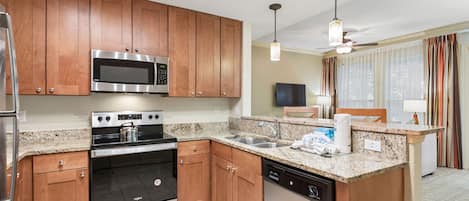 A modern kitchen with wooden cabinets, stainless steel appliances, granite countertops, and a dishwasher.