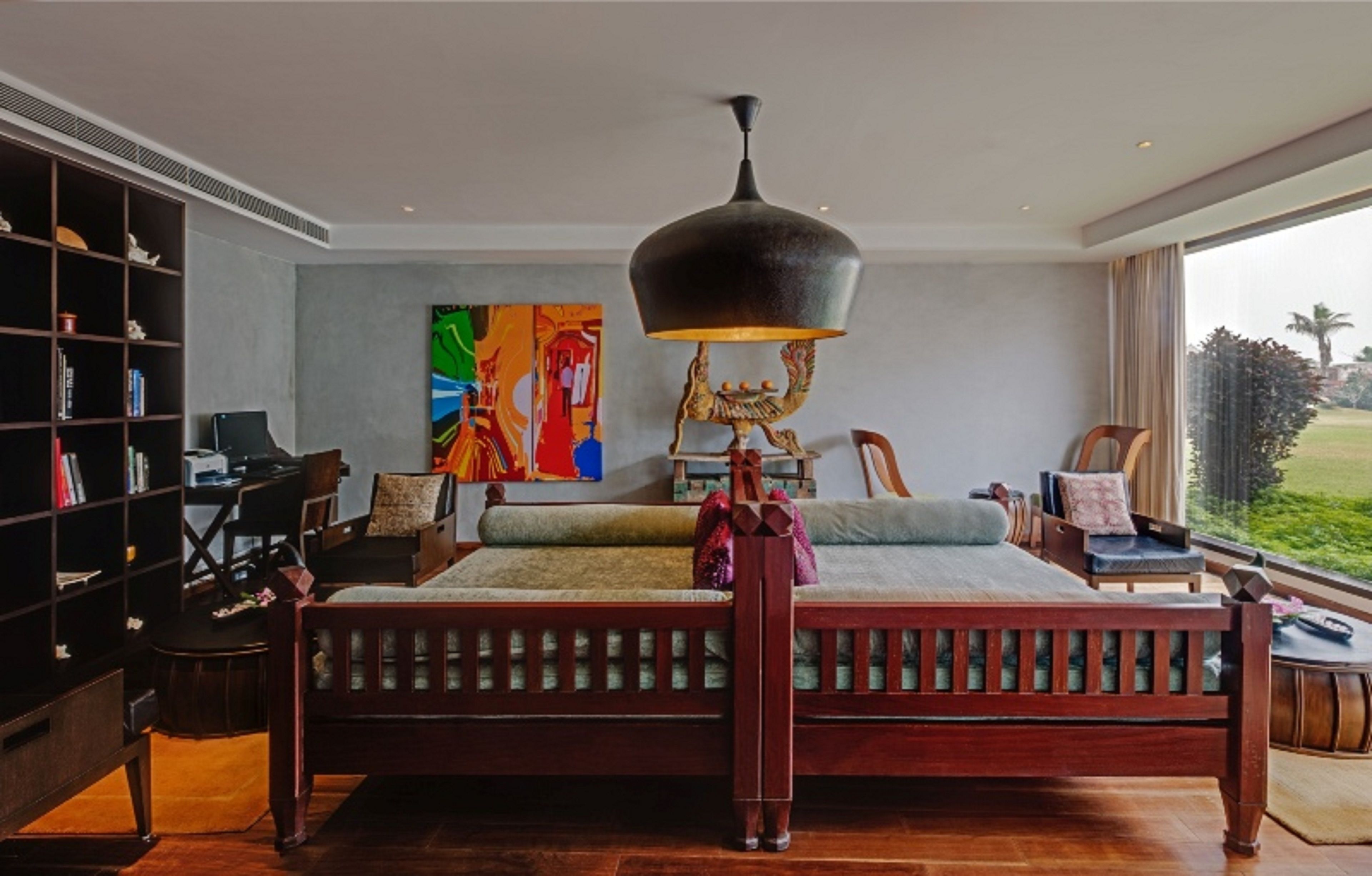 Une chambre à coucher avec un lit en bois, une bibliothèque, un bureau et une grande fenêtre donnant sur un paysage verdoyant.