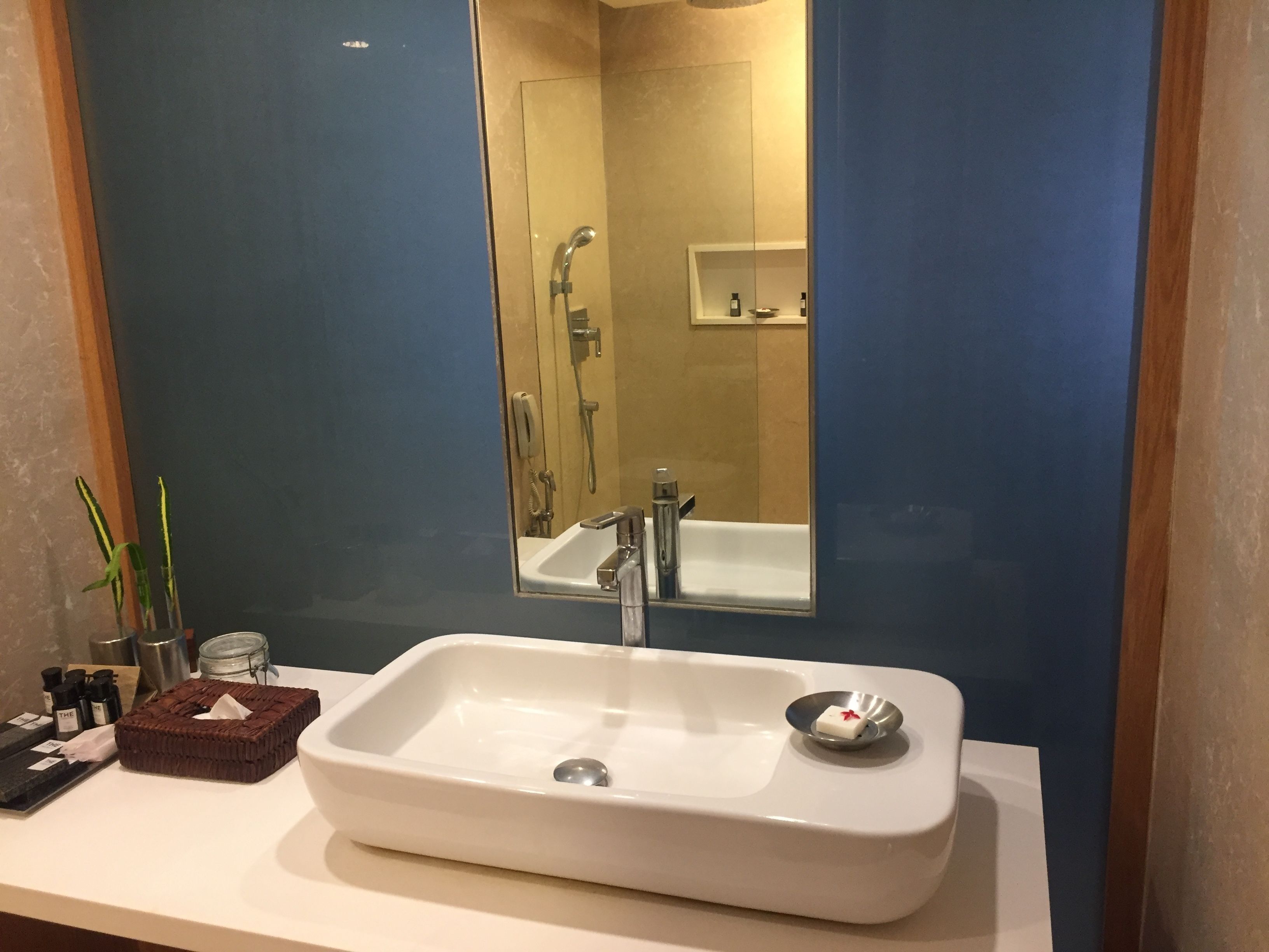 A bathroom with a white sink, a mirror, and a blue wall.