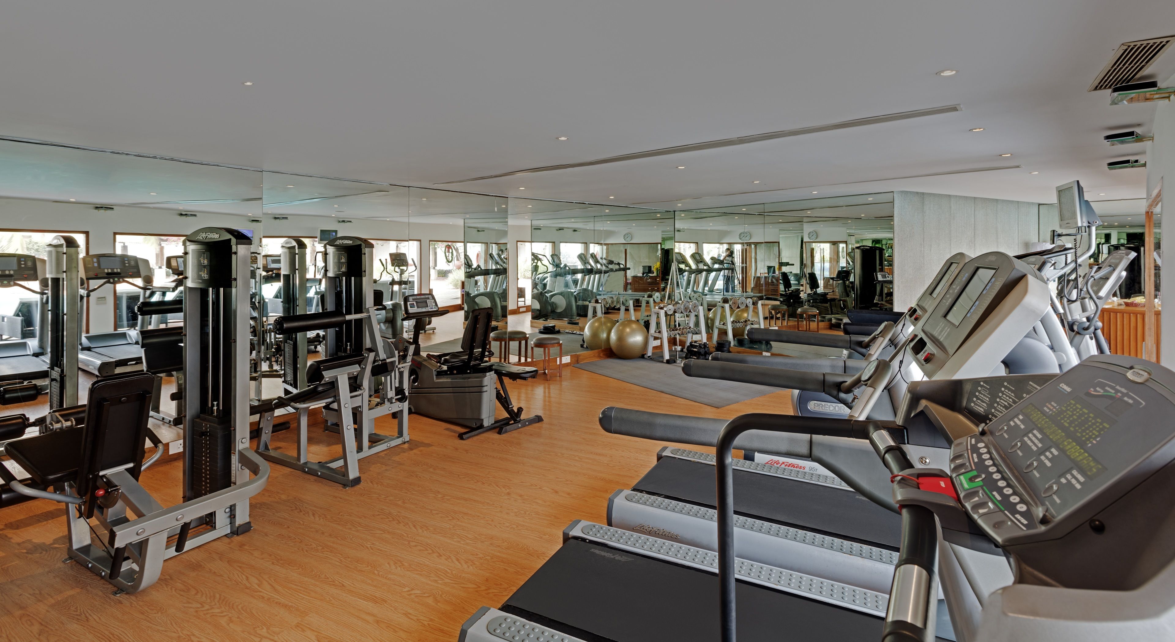 Ein geräumiges Fitnessstudio mit Laufbändern, Kraftgeräten und Gymbällen.