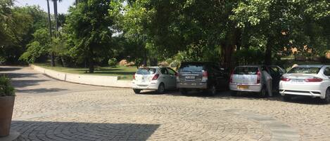 Un área pavimentada con tres coches estacionados bajo árboles.