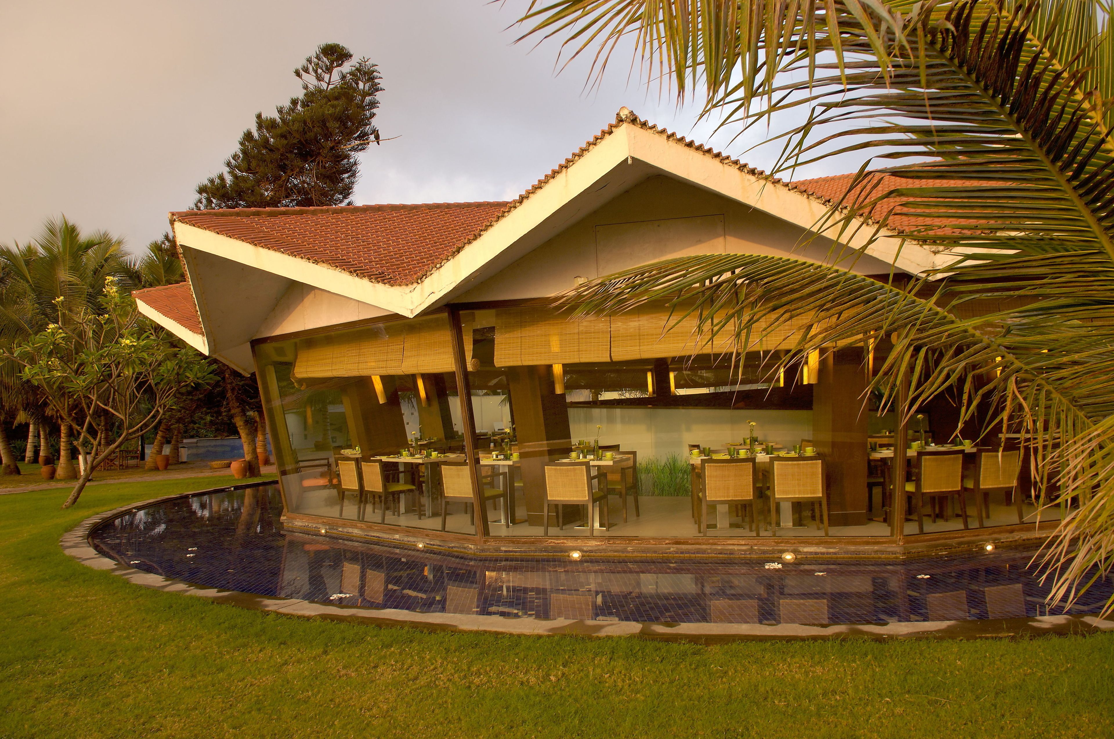 Un restaurante con terraza, piscina y jardín tropical.