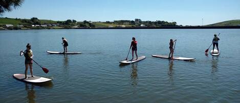 Een groep mensen staat op paddleboards op een kalm meer met een heldere lucht.
