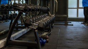 A gym with weightlifting equipment, including dumbbells and barbells, and exercise machines.