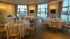 A dining area with round tables, chairs, and a view of the water.