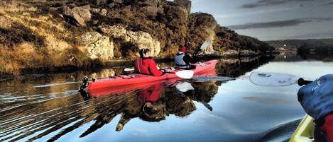 Un río tranquilo con kayaks, una orilla rocosa y un cielo despejado.