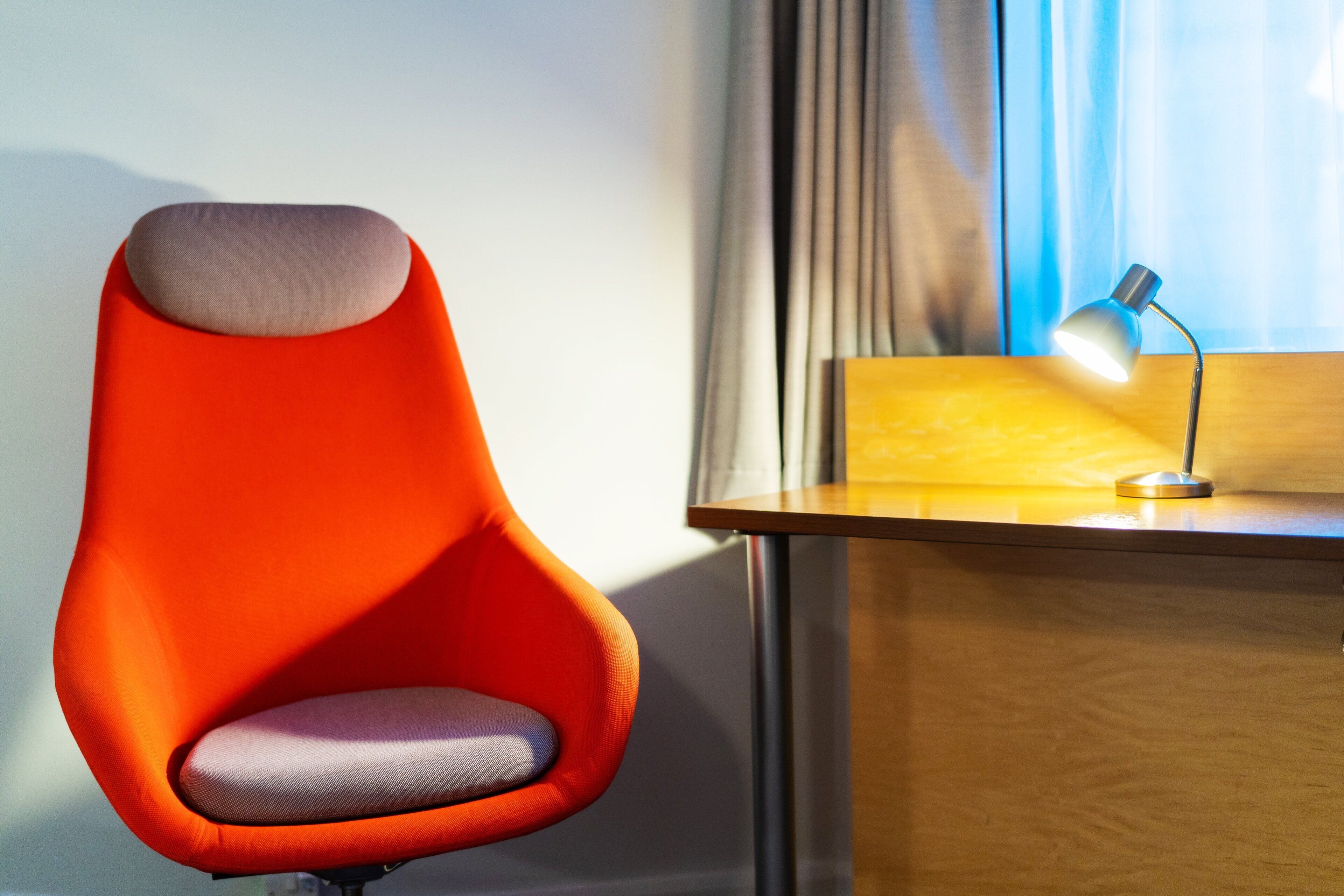 Ein moderner Stuhl mit einzigartigem Design, ein Holztisch und eine Schreibtischlampe.