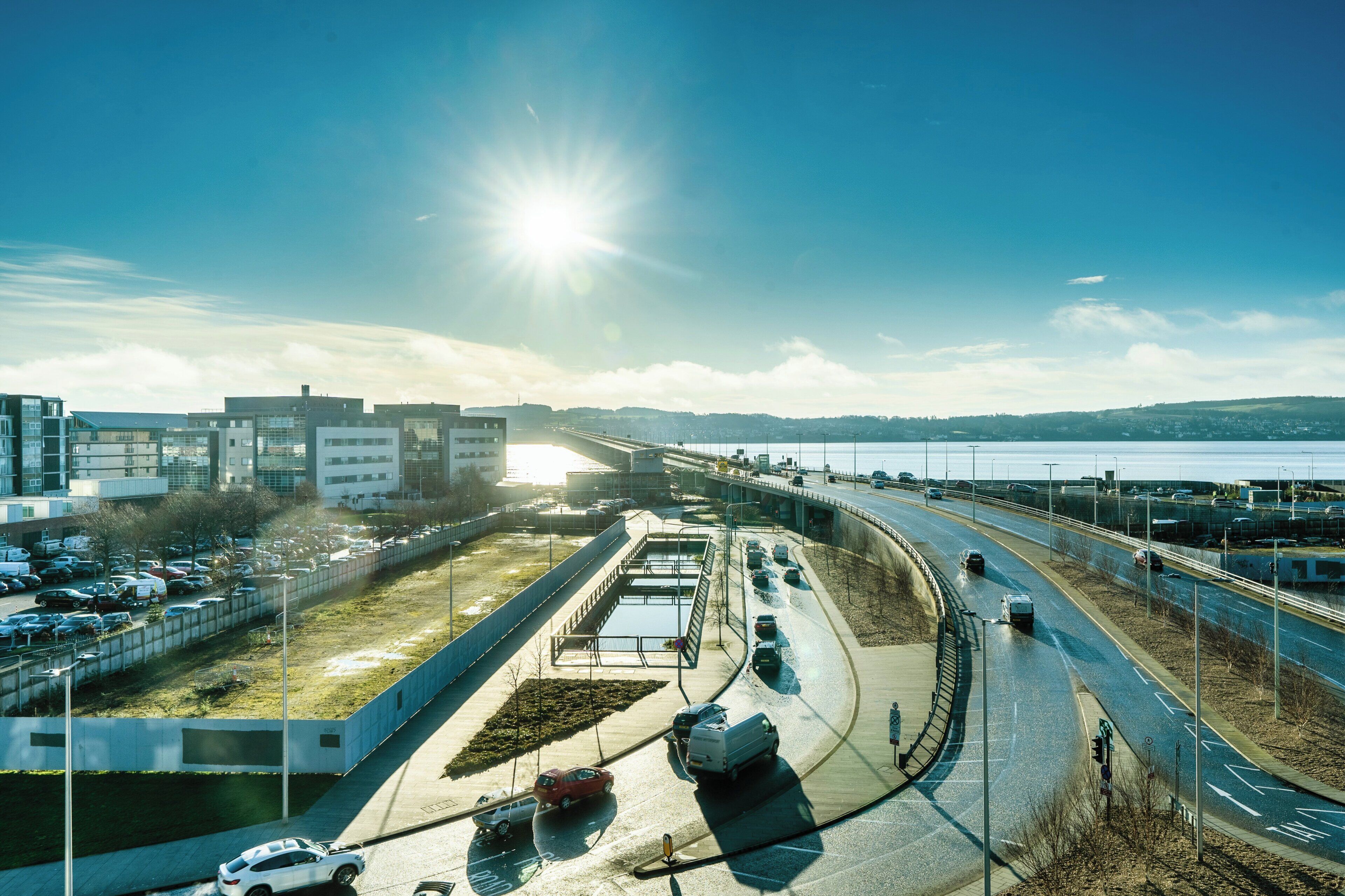 A highway with vehicles, a bridge, and buildings in the background.
