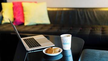 A laptop on a table with a cup of coffee and a plate of cookies.