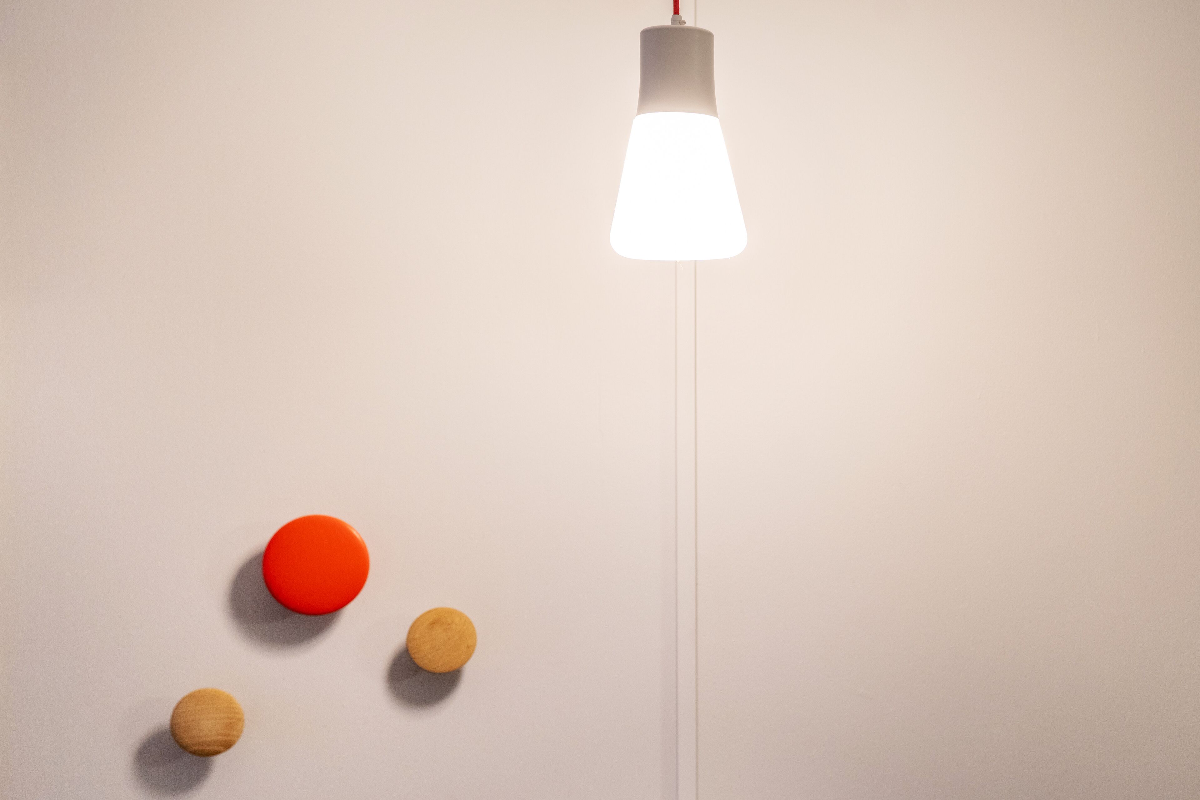 A minimalist room with a white wall and a hanging light fixture.