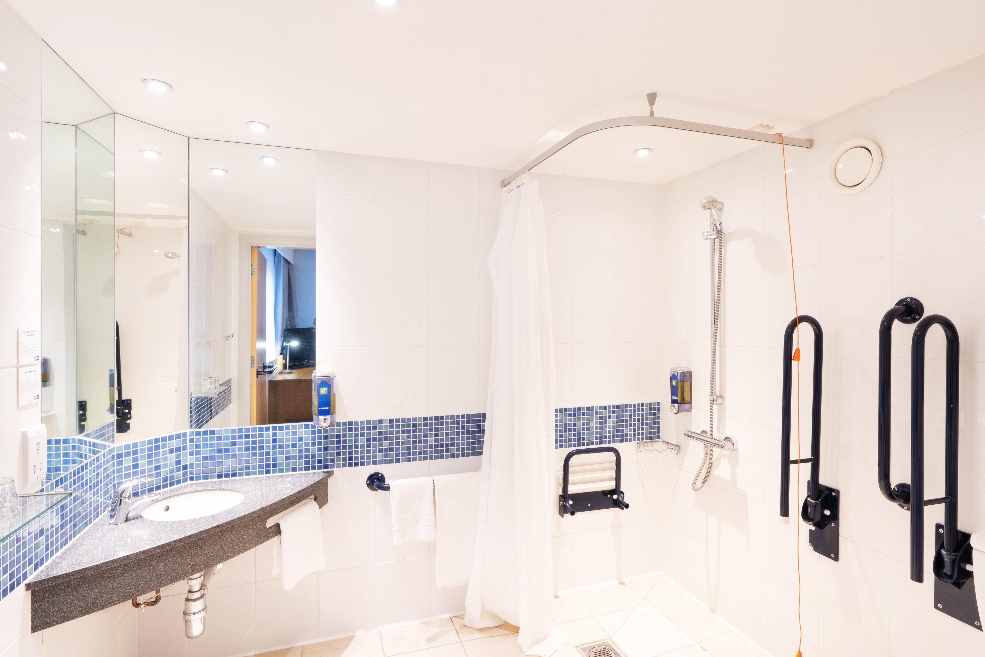 Un baño moderno con cabina de ducha de vidrio, un lavabo con toallero y un espejo.