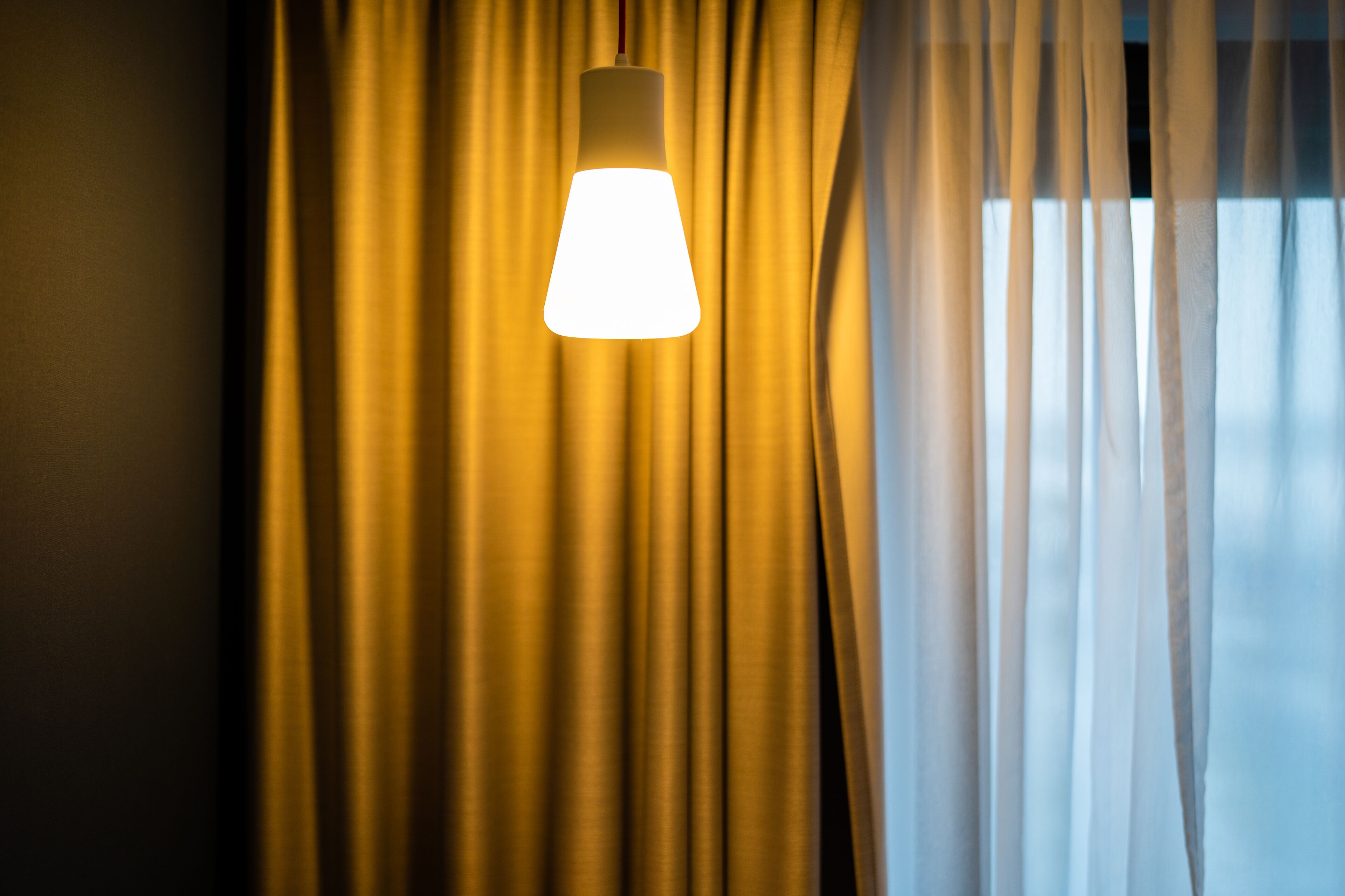 Una lámpara colgante frente a cortinas.
